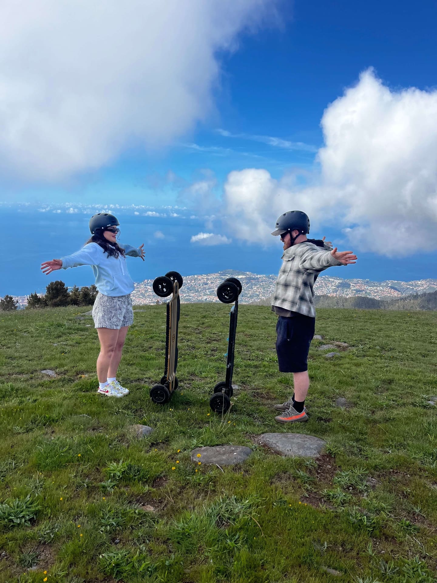 Couple with arms out next to e-boards on a Madeira mountain summit